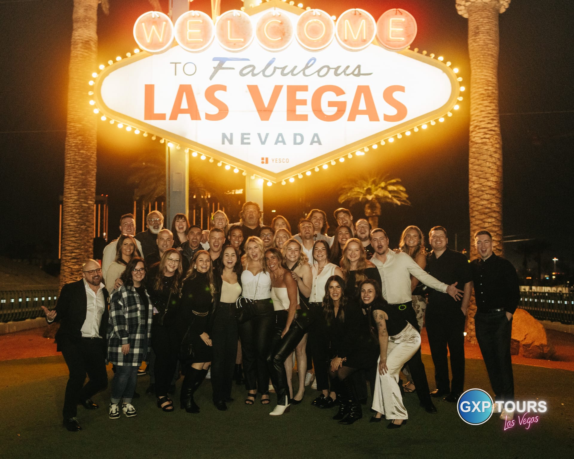 Large company team gathered at the Welcome to Las Vegas sign on a GXP Tours private night out